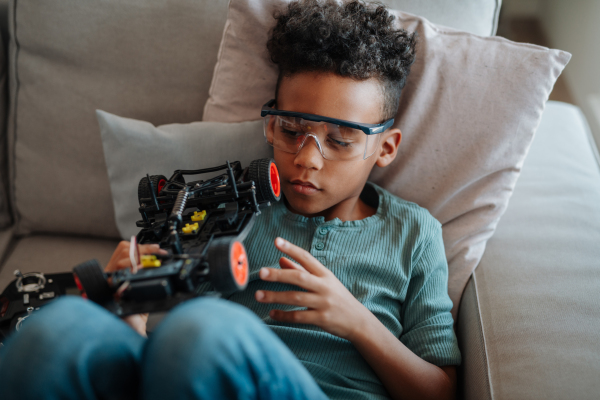Focused boy building and programming robot car at home as part of STEM learning.