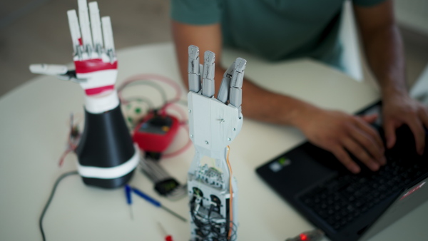 Close up of young engineer building and programming a robotic arm at home. Robotics concept.