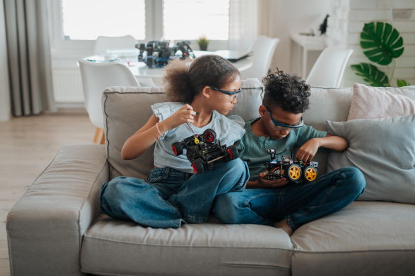 Siblings building and programming robot car at home as part of STEM learning.