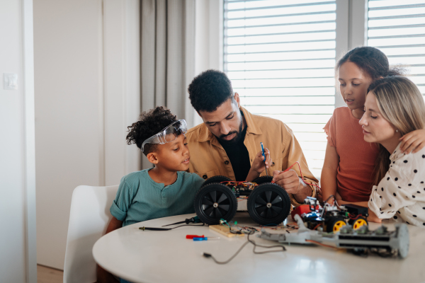 Parents building toy robotic kit with their two kids. Robotic car assembling.