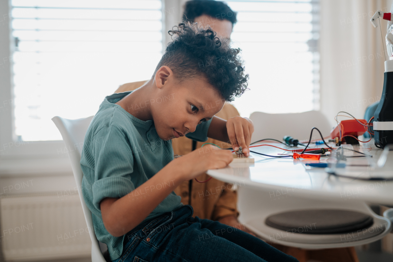 Young schoolboy assembling robotic kit and working with circuit board at home.