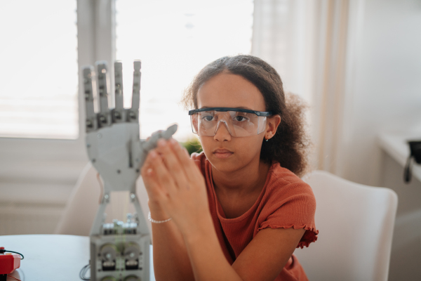 Cute girl admiring robotic hand. STEM learning.