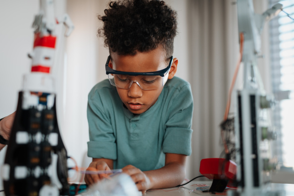 Focused boy working on small robot toy at home as part of STEM learning.