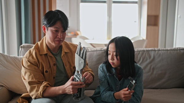 Father teaching his curious daughter about STEM, robotics, and discussing technology.
