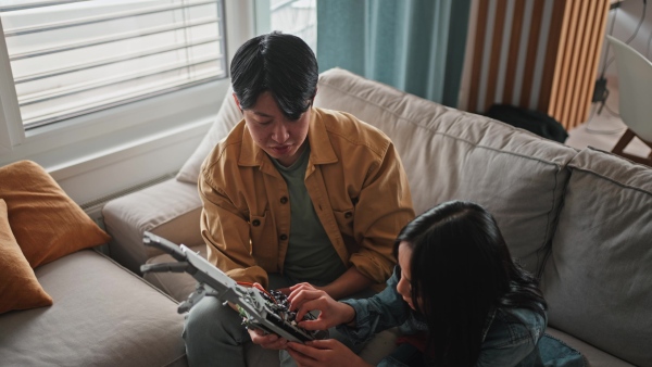 Father teaching his curious daughter about STEM, robotics, and discussing technology.