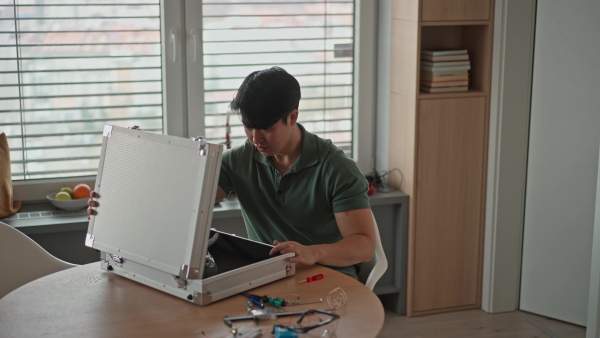 Young engineer building and programming a robotic arm at home. Robotics concept.