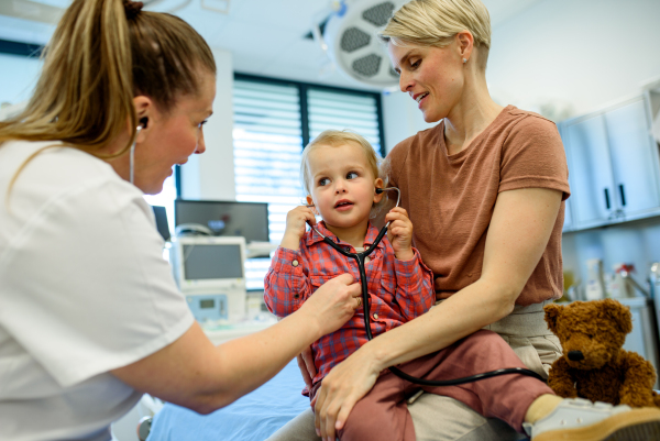 Little boy trying pediatrician's stethoscope during medical examination in doctor's office.