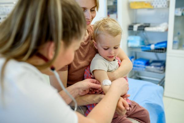 Doctor placing cotton and medical tape on the injection spot. Preventive care.