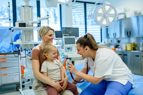 Female doctor listening little boy's heartbeat and breathing during preventive medical checkup.