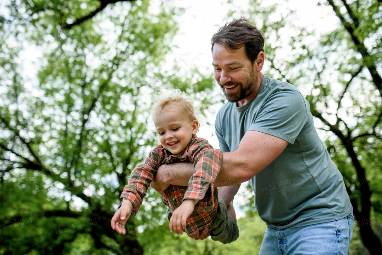 Father playing with toddler son outdoors in city park