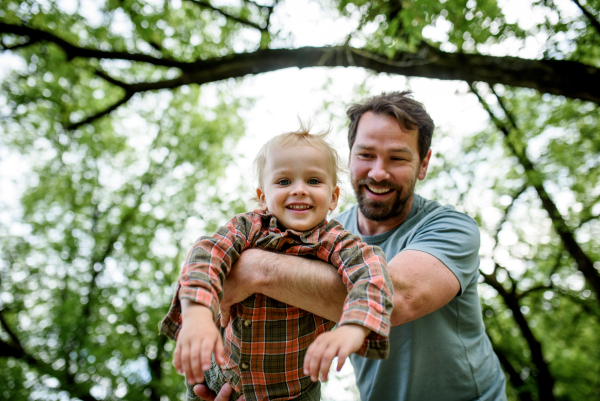 Father playing with toddler son outdoors in city park