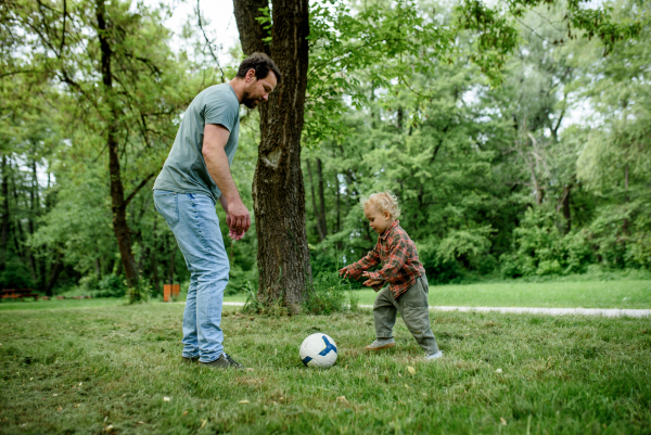 Father and son playing football together in a park