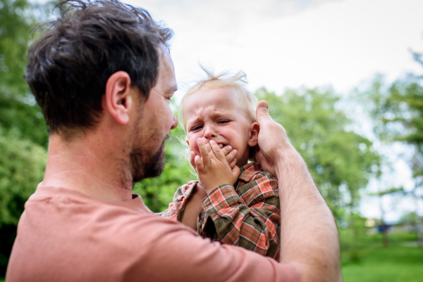 Loving father helping to injured crying toddler boy. Fatherhood concept.