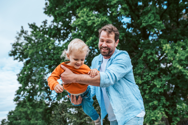 Father playing with toddler son outdoors in city park