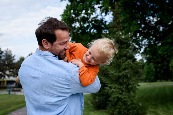 Father playing with toddler son outdoors in city park