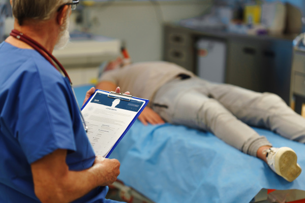 Medical professional examining health record patient lying on examination table. emergency room setting.
