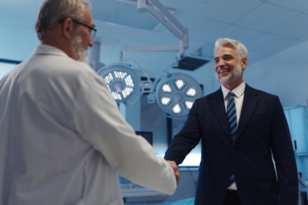 Portrait of pharmaceutical sales representative shaking hand with doctor. Hospital director, manager of private medical clinic.