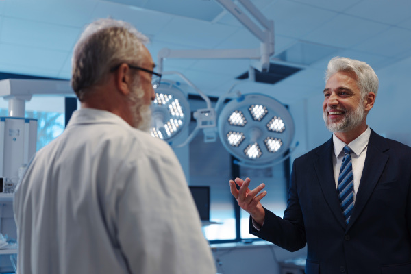 Hospital director talking with doctori in examination room. Hospital setting.