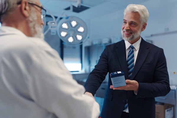 Portrait of pharmaceutical sales representative shaking hand with doctor. Hospital director, manager of private medical clinic.