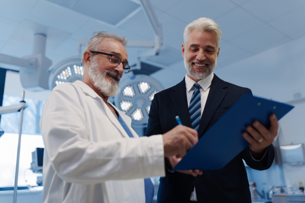 Doctor signing contract with pharmaceutical representative, successful deal.