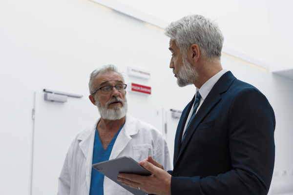 Doctor talking with hospital manager, showing him document.