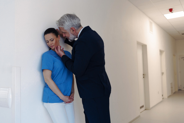 Pharmaceutical representative or hospital manager harassing attractive nurse in healthcare setting.