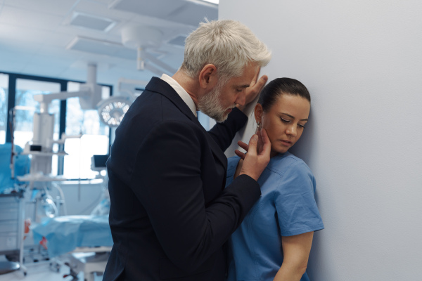 Pharmaceutical representative or hospital manager harassing attractive nurse in healthcare setting.