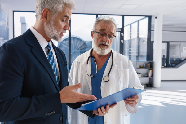 Doctor talking with hospital manager, walking down the hospital hallway.