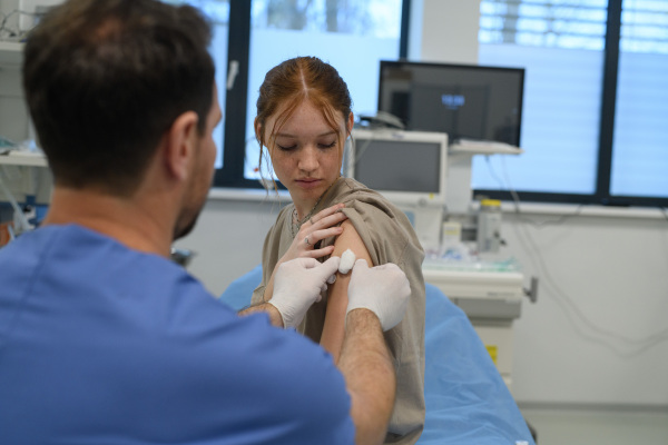 Teenage girl receiving vaccination during routine health checkup at hospital.