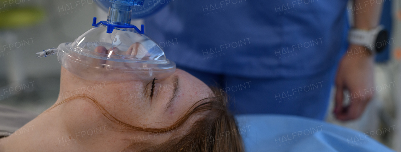 Medical staff applying oxygen mask to unconscious teenage girl in hospital. Banner with copy space.