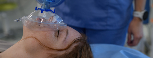 Medical staff applying oxygen mask to unconscious teenage girl in hospital. Banner with copy space.