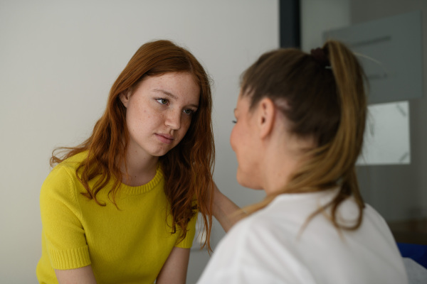 Doctor offering reassurance to frightened teen patient before examination.