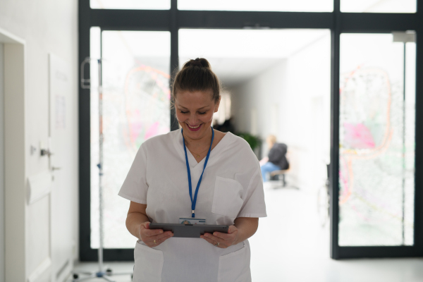 Portrait of nurse reading patient appointment list on digital tablet in hospital.