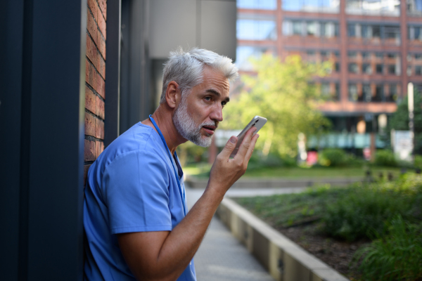 Doctor is recording a voice message to his family saying he has to stay late at work.