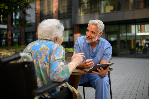 Healthcare professional in nursing home explaining medical results, using tablet.