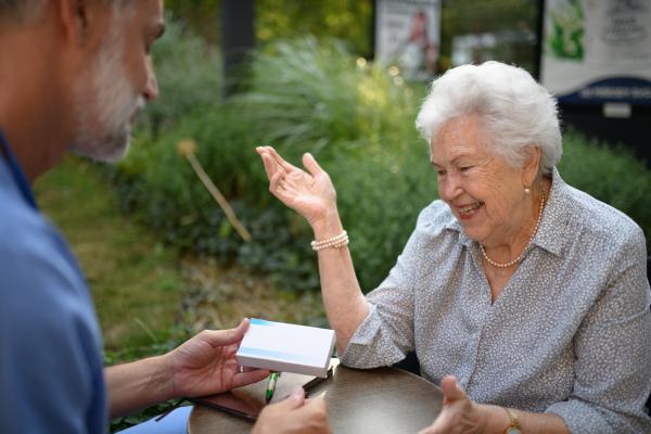 Doctor explaining medication to senior patient and answering her questions about diagnosis.