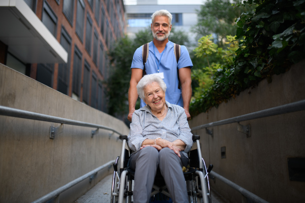 Male caregiver pushing senior woman in a wheelchair.