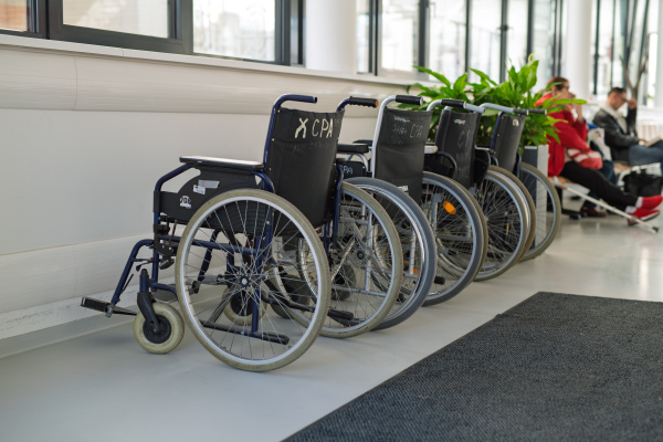 Set of empty hspital wheelchairs in hospital hallway.