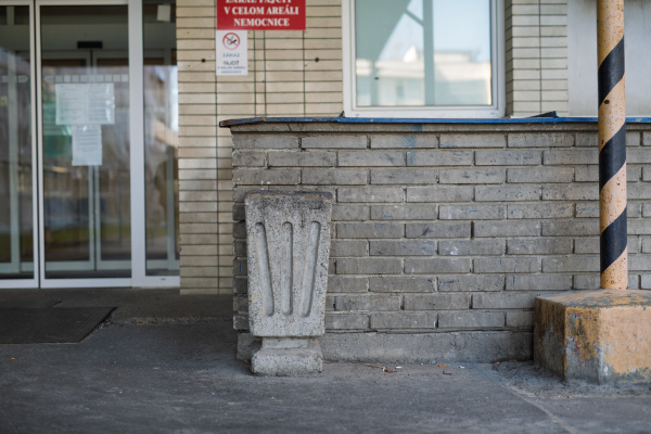 Main hospital entrance with worn facade and litter bin.