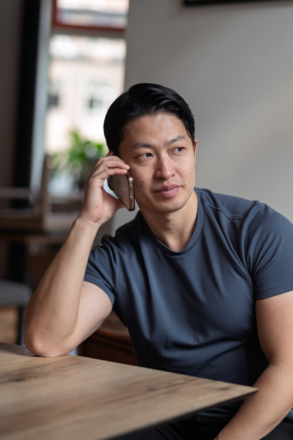 Confident young man having phone call at cafe table.