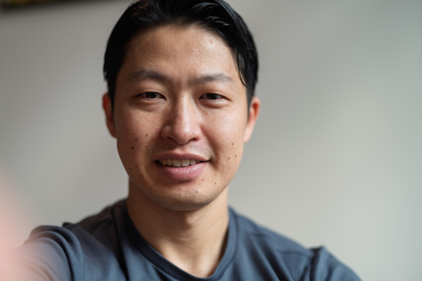Portrait of young handsome Asian man, looking at camera and smiling.