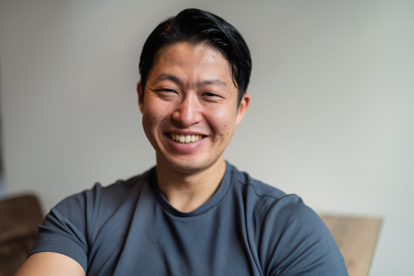 Portrait of young handsome Asian man, looking at camera and smiling.
