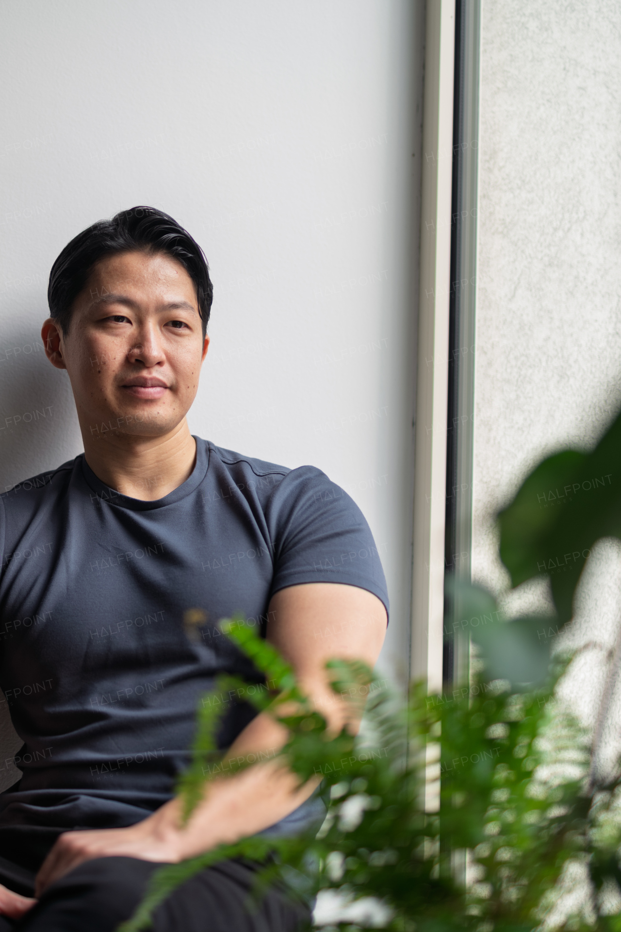 Confident young man sitting by the window in natural light, resting.