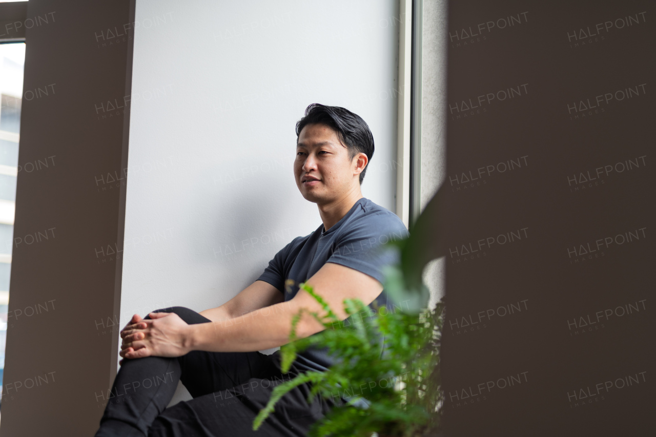 Confident young man sitting by the window in natural light, resting.
