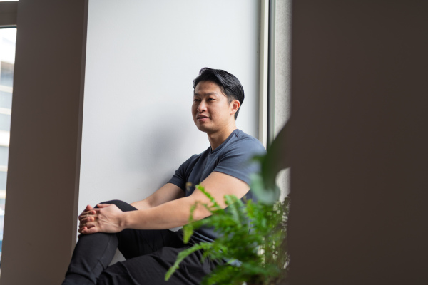 Confident young man sitting by the window in natural light, resting.
