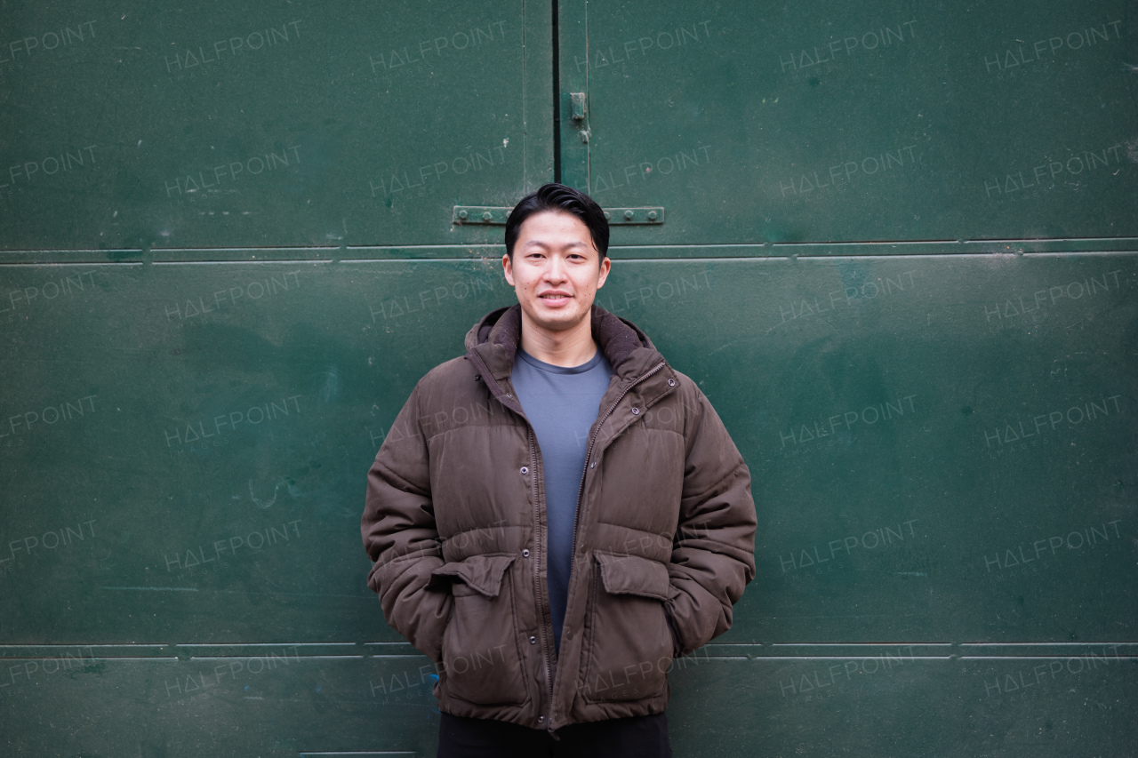 Portrait of young handsome Asian man outdoors during cold day. Looking at camera.
