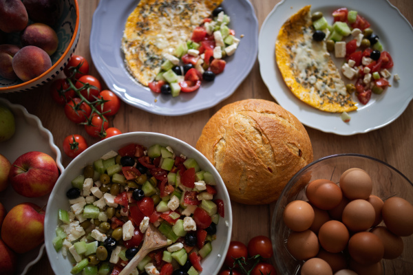 Omelet with Greek salad and fresh bread. Colorful Mediterranean breakfast.