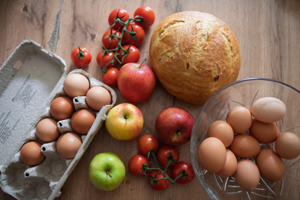 Fresh ingredients for homemade breakfast. Eggs, bread and fruit on rustic wooden table.
