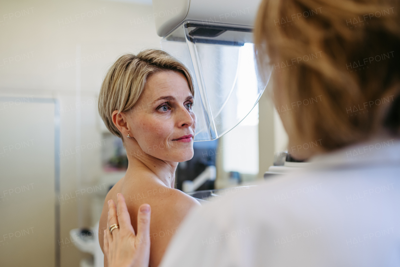 Medical professional calming patient ahead of mammogram procedure. Preventive breast cancer screening.