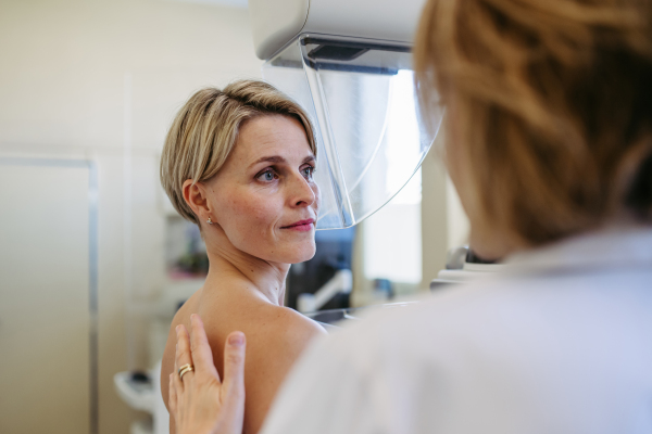 Medical professional calming patient ahead of mammogram procedure. Preventive breast cancer screening.